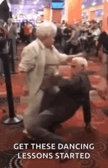 an older couple is dancing in a crowded room .