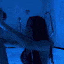 a woman is floating in a bathtub with a blue light behind her .