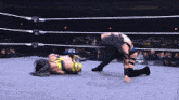 two women are wrestling in a ring with a w logo on the wall behind them