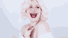 a woman in a blonde wig and red lipstick is laughing with her mouth open .