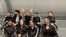 a group of people wearing black jackets with the word emily on them are sitting on a bench