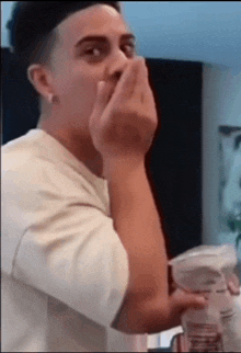 a man in a white shirt is covering his mouth with his hands