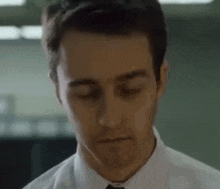 a man in a white shirt and tie is looking down at something .