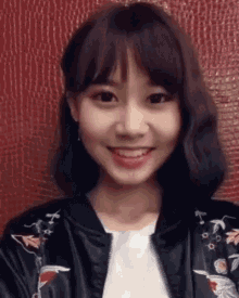 a close up of a woman wearing a bomber jacket and smiling