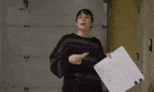 a woman in a black sweater is holding a piece of paper that says " i love you " .