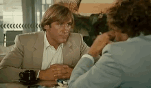 a man in a suit sits at a table with a woman