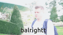 a man with a backpack is standing in front of a hedge with the words balrightt on the bottom .