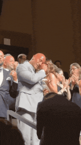 a man in a suit is kissing a woman in a crowd