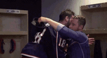 two men hugging in a locker room and one has the number 18 on his jersey