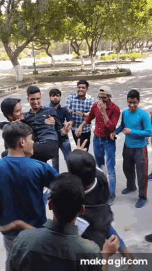 a group of young men are standing in a circle and one of them is carrying another man
