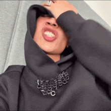a close up of a person wearing a black hoodie with chains around their neck