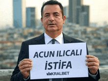 a man in a suit and tie is holding up a sign that says acun ilicali istifa