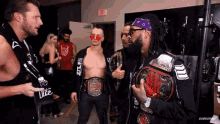 a group of wrestlers are standing in a room with an exit sign