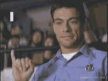 a man in a blue shirt is making a middle finger gesture .