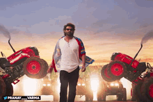 a man standing in front of a row of red tractors with the hashtag pranay_varma on the bottom