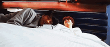 two men are laying on a bed with their heads on each other and smiling .