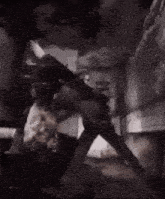 a black and white photo of a person standing in a dark room with a smoke coming out of the ceiling .