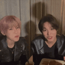two young men are sitting at a table with a plate of food in front of them .