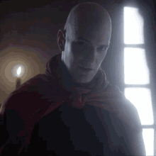 a bald man with a red cape around his neck looks at the camera