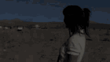 a woman is standing in the middle of a desert holding an apple .
