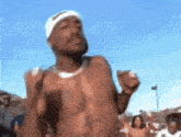 a shirtless man wearing a headband is dancing in front of a crowd .