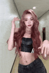 a woman with long red hair is wearing a black crop top and gray jeans .