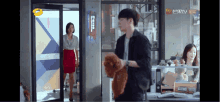 a man is holding a teddy bear in front of a woman in an office