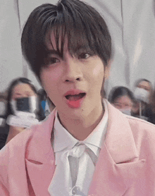 a young man wearing a pink jacket and a white shirt is making a funny face .