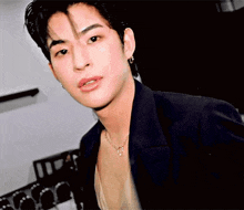 a close up of a young man wearing a black jacket and a necklace .