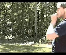 a man with glasses is standing in front of trees