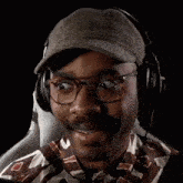 a man wearing a hat and headphones is smiling while sitting in a chair .