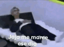 a man is laying on a bed with the words `` jaja me mame ese dia '' written above him .