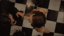 a man and a woman are dancing together on a checkered floor