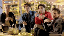 a group of young men are sitting around a table with bottles