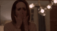 a woman is covering her face with her hands in a living room .