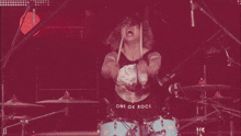a man wearing a shirt that says one ok rock is playing drums