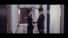 a man and a woman are standing next to each other in a hallway looking at each other