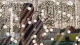 a woman in a black dress is standing in front of a fence covered in christmas lights .