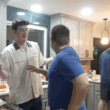 a man in a bowling shirt talks to another man in a blue shirt
