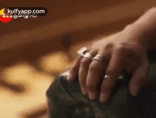 a close up of a person 's hands with rings on their fingers