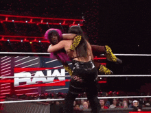 two women wrestling in a ring with a raw logo in the background