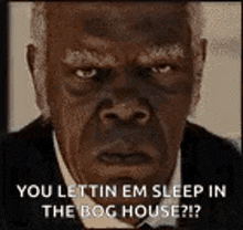 a man in a suit and tie is making a funny face and says `` you lettin em sleep in the bog house ? ''