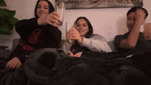 three people sitting on a couch with one wearing a shirt that says s
