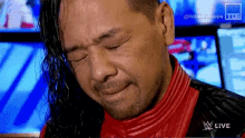 a man in a red leather jacket is crying while watching a wrestling show .