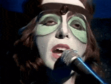 a woman wearing a mask is singing into a microphone .