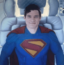 a man in a superman costume is smiling while laying in a chair