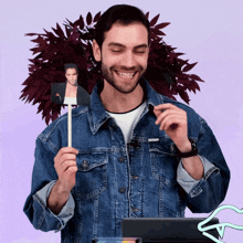 a man in a denim jacket is holding up a picture of a man