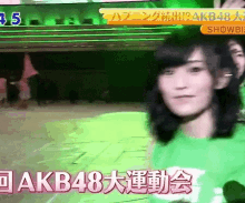 a woman is wearing a green shirt with akb48 written on it