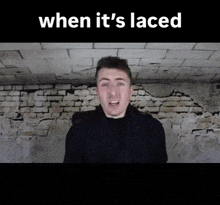 a man is standing in front of a brick wall with the words when it 's laced above him