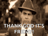 a man in a suit and hat is standing in front of a sign that says thank god it 's friday .